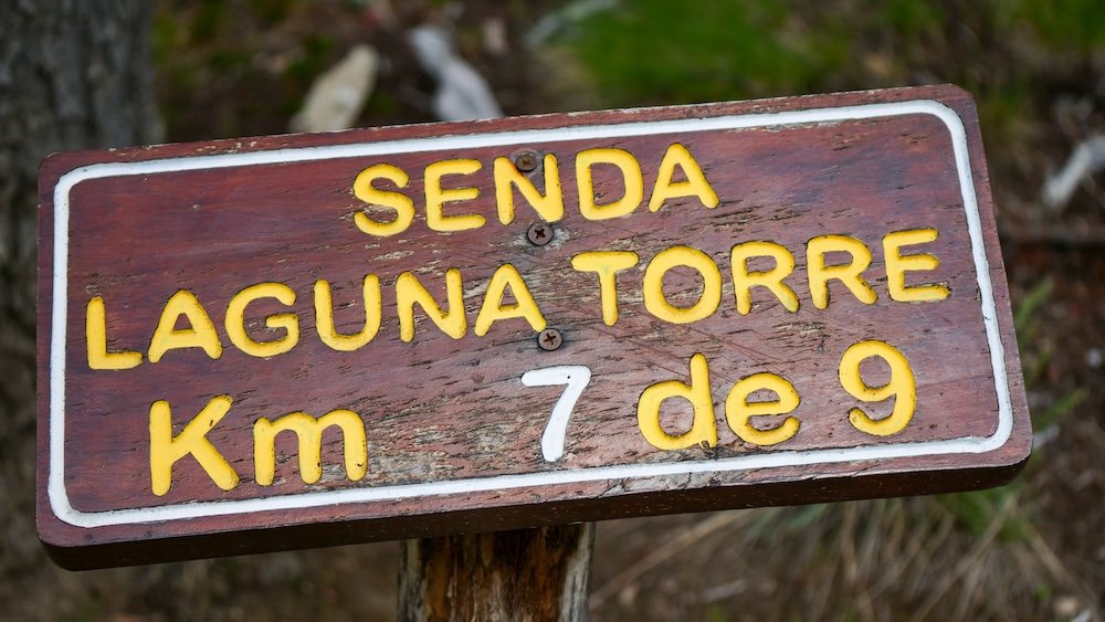 Laguna Torre trail sign in El Chaltén, Patagonia, marking kilometer 7 of 9—an encouraging checkpoint for hikers nearing the end of this popular route toward Cerro Torre and the glacier-fed lagoon.
