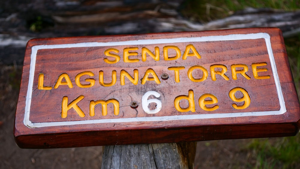 El Chaltén Laguna Torre trail marker reading “Senda Laguna Torre Km 6 de 9,” guiding hikers along Patagonia’s iconic trek and showing distance progress on the scenic route toward the glacier lagoon for pacing and weather decisions.