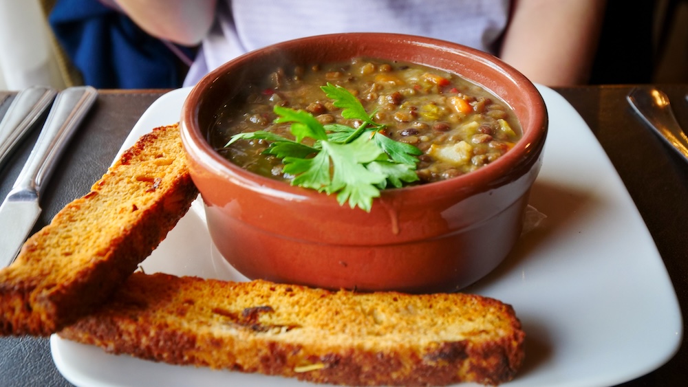 El Chaltén Patagonia lentil stew served at Senderos restaurant, a hearty lentejas dish with toasted bread that hikers enjoy as a warm and comforting meal after long treks to Fitz Roy, Laguna Torre and Laguna de los Tres in Los Glaciares National Park.