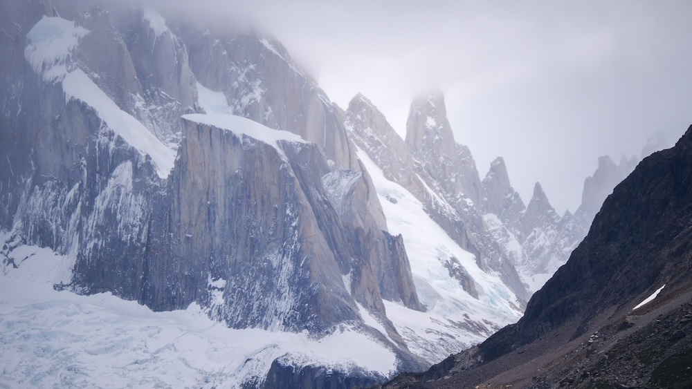 El Chaltén’s Fitz Roy massif under moody cloud cover and drifting mist, showing dramatic Patagonian mountain weather conditions hikers experience when visibility shifts and peaks hide behind storms.