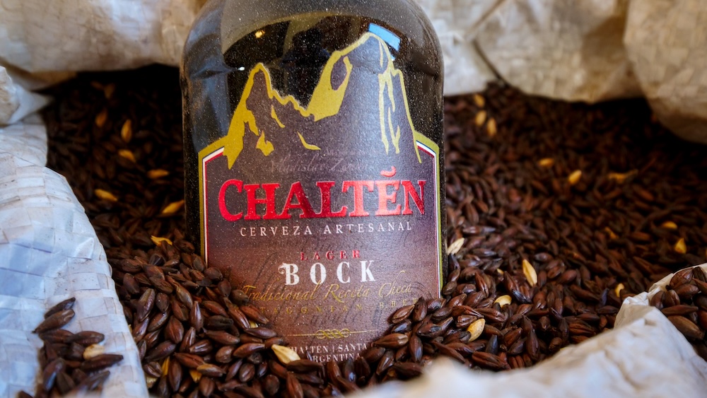 Chaltén Cerveza Artesanal craft beer in El Chaltén El Chaltén, Patagonia, Argentina — a bottle of Chaltén Cerveza Artesanal Bock resting on roasted malt grains, showcasing the town’s local craft beer culture enjoyed by hikers after long days on the trails.