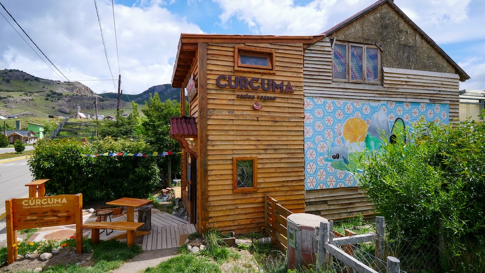 Cúrcuma healthy food restaurant in El Chaltén El Chaltén, Patagonia, Argentina — the wooden exterior of Cúrcuma restaurant with colorful mural and garden seating, a popular spot for healthy and vegetarian meals after long days hiking the Patagonian trails.