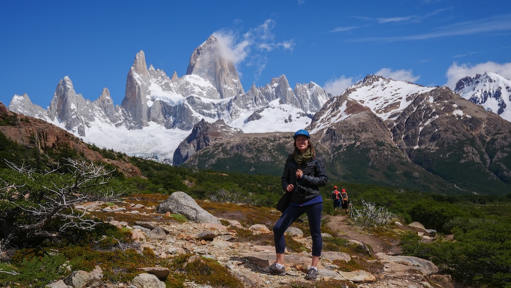 El Chaltén, Patagonia, Argentina trail on the Laguna de los Tres hike with Audrey Bergner smiling in front of the Fitz Roy massif, showing the dramatic payoff reached after a long and physically demanding mountain trail