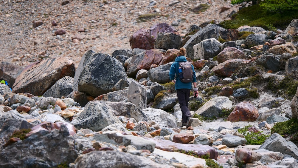El Chaltén Patagonia Argentina rugged hiking trail near Laguna Torre where a lone backpacker walks through a rocky glacial landscape surrounded by boulders and alpine terrain on the scenic trek toward Cerro Torre in Los Glaciares National Park.
