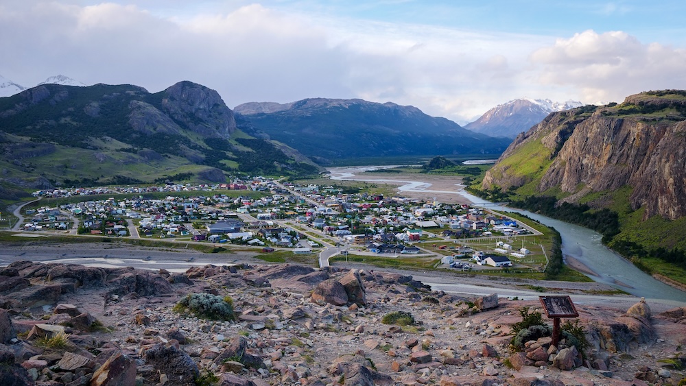 El Chaltén, Patagonia, Argentina aerial viewpoint from Mirador de los Cóndores, showing the town, river valley, and surrounding cliffs, illustrating the rewarding payoff reached after a short but steep hiking climb