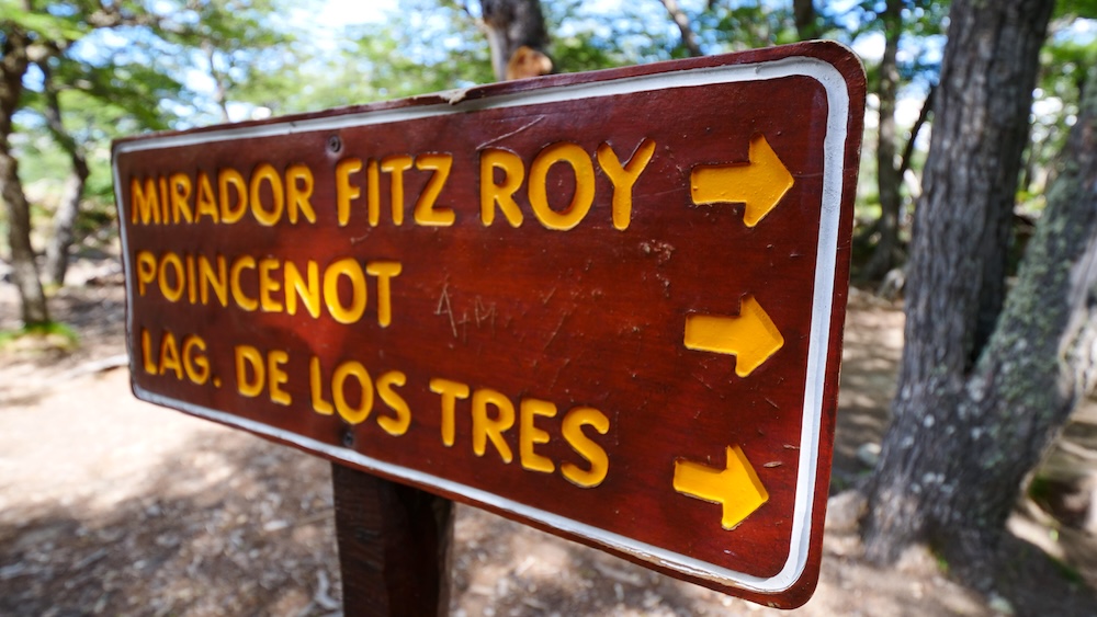 El Chaltén, Patagonia, Argentina trail sign pointing toward Mirador Fitz Roy, Poincenot, and Laguna de los Tres, featuring a wooden directional marker guiding hikers through lenga forest on the classic trekking route