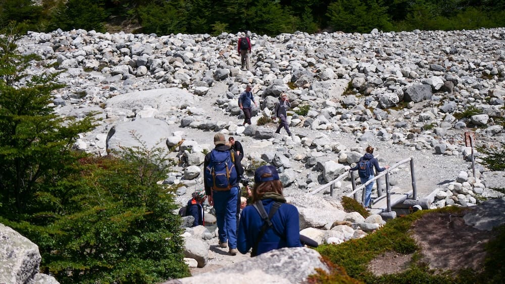 El Chaltén, Patagonia, Argentina popular hiking trail crowded with groups of trekkers navigating rocky terrain and footbridges, showing how famous routes can quickly fill up during peak hours, especially on well-known hikes that attract many visitors in summer.