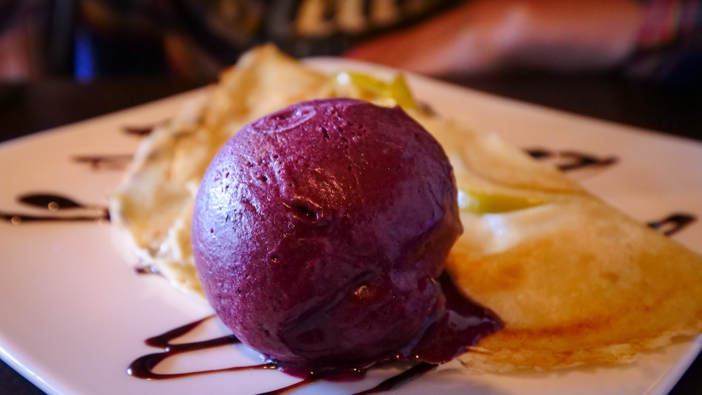 Serve-every-bite dessert crepe in El Chaltén El Chaltén, Patagonia, Argentina — a scoop of rich berry ice cream served over a warm crepe with chocolate drizzle, a serve-every-bite dessert moment after a long day hiking Patagonia’s mountain trails.