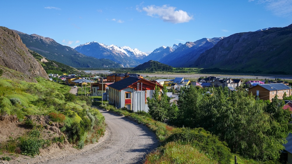 El Chaltén, Patagonia, Argentina town view from an uphill path, showing colorful buildings, the Río de las Vueltas valley, and surrounding mountains, illustrating the compact base where all hiking trails begin