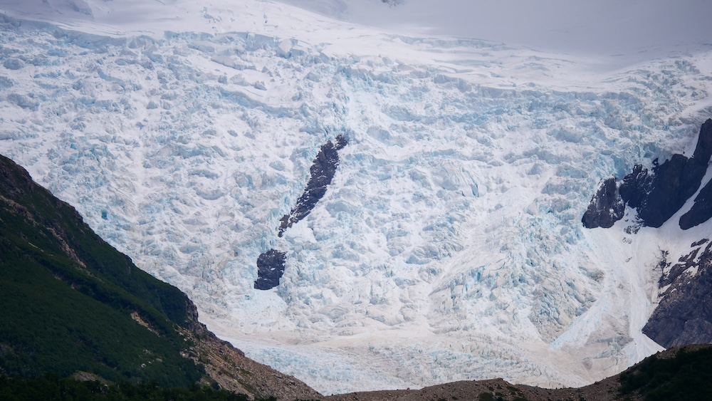 El Chaltén, Patagonia — a massive blue-white glacier spills down a steep mountainside, revealing raw ice textures and crevasses that showcase the untamed natural beauty of Argentina’s Los Glaciares National Park.