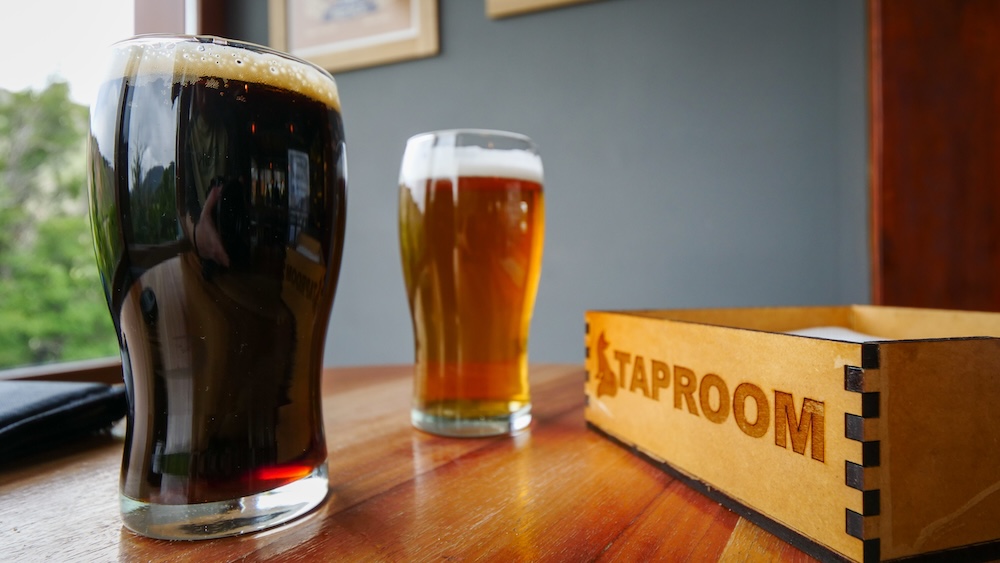 El Chaltén, Patagonia — dark stout and golden craft beer at La Zorra Taproom sit on a wooden table by the window, the perfect post-hike reward after a long day exploring the trails around Argentina’s hiking capital.