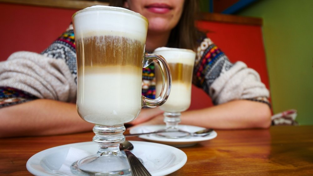 El Chaltén, Patagonia: layered latte coffees sit on a café table during a recovery day between hikes, highlighting how warm drinks, cozy cafés, and slow mornings are an essential part of resting legs after big trails like Laguna de los Tres and Laguna Torre.
