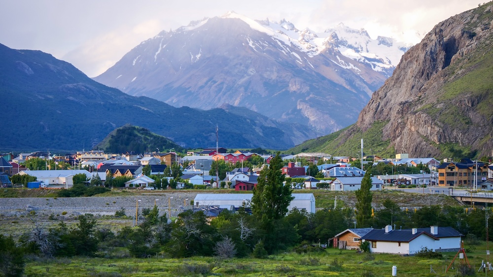 El Chaltén town nestled beneath Patagonian mountains, showing a peaceful day-off scene where hikers relax, explore village streets, and enjoy recovery time between trail adventures in changing mountain weather.
