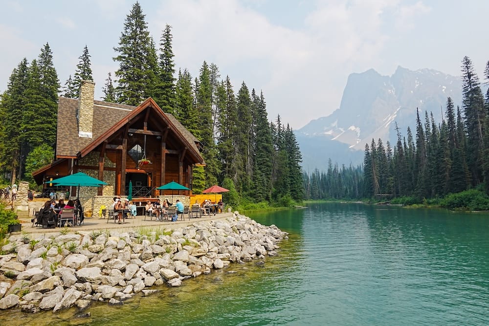 Lakeside lodge and patio at Emerald Lake in Yoho National Park, British Columbia, Canada A rustic lakeside lodge and outdoor patio overlook the green water of Emerald Lake in Yoho National Park, British Columbia, Canada, with evergreen forest and a steep mountain ridge rising behind.