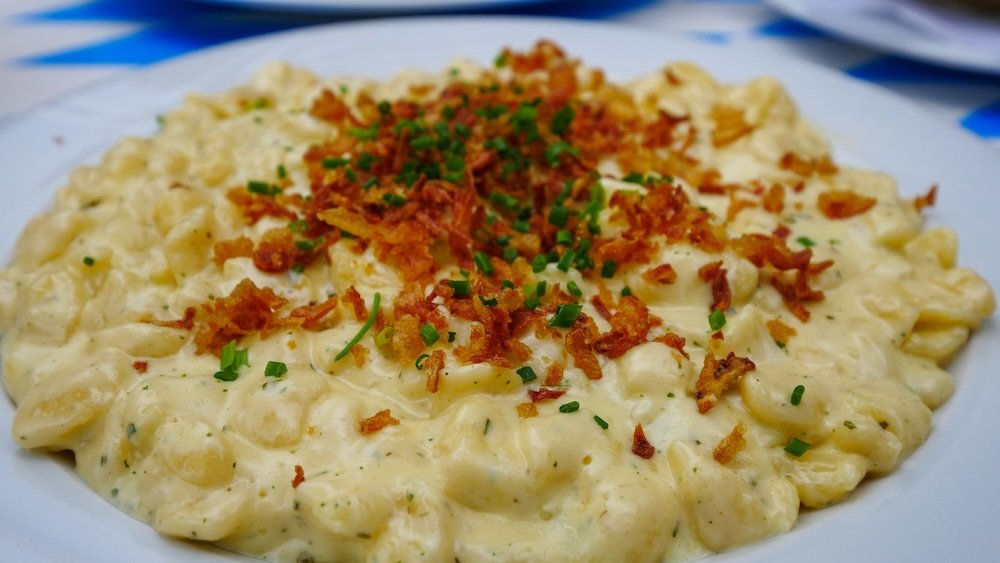 Enjoying a plate of Kässpatzen Cheesy dumpling noodles layered with caramelized onions in the German Alps