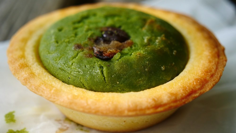 Enjoying matcha cheese tarts as a street food snack in Mount Takao, Japan 