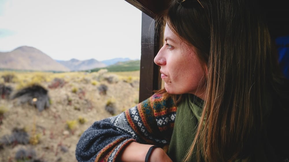 Audrey Bergner looking out from La Trochita train near Esquel in Patagonia Argentina observing the Patagonian steppe landscape during a scenic journey that connects coastal regions with the Andes mountains.