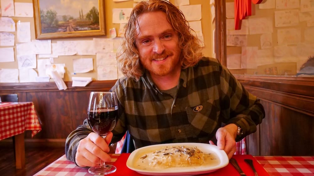 Samuel Jeffery enjoying pasta and wine in Esquel Patagonia Argentina where restaurant pricing can be confusing for visitors, as dishes like pasta are often priced separately from sauces leading to unexpected costs
