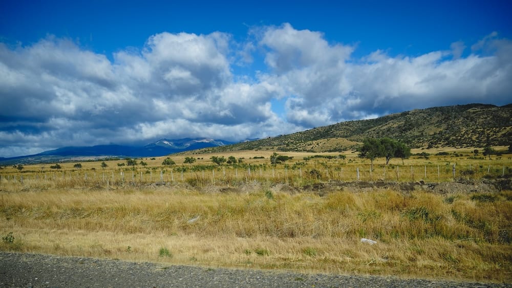 Esquel to Trevelin Patagonia scenic drive Chubut Argentina Andes landscape Welsh Patagonia route Scenic Patagonian landscape between Esquel and Trevelin in Chubut Argentina featuring open steppe, rolling hills, and distant Andes mountains under dramatic clouds, capturing the remote journey through Welsh Patagonia