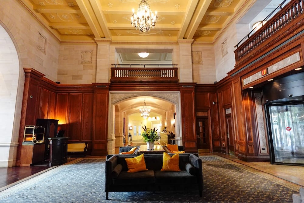 Gran lobby principal con techos altos y arañas en el Fairmont Hotel Macdonald en Edmonton, Alberta, Canadá El gran lobby principal del Fairmont Hotel Macdonald cuenta con techos altos abovedados, candelabros elegantes, paneles de pared de madera oscura y asientos cómodos en Edmonton, Alberta, Canadá.