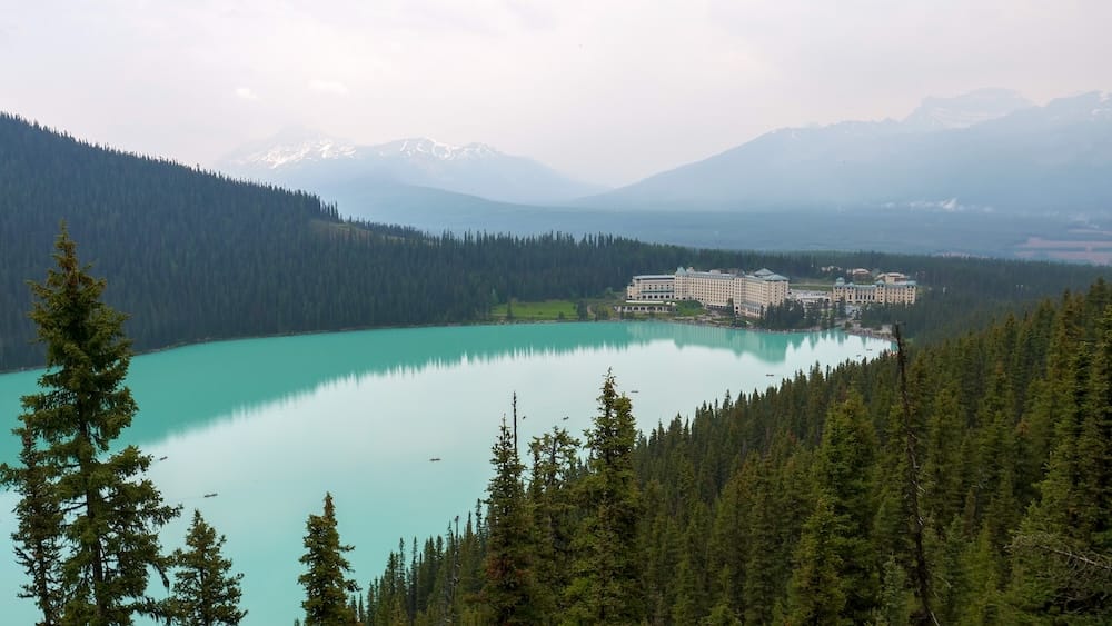 La vista desde Fairview Lookout sobre Lake Louise en el Parque Nacional Banff, Alberta, Canadá, mostrando el lago turquesa, el bosque alrededor y el Fairmont Chateau Lake Louise desde un ángulo elevado sobre la orilla.