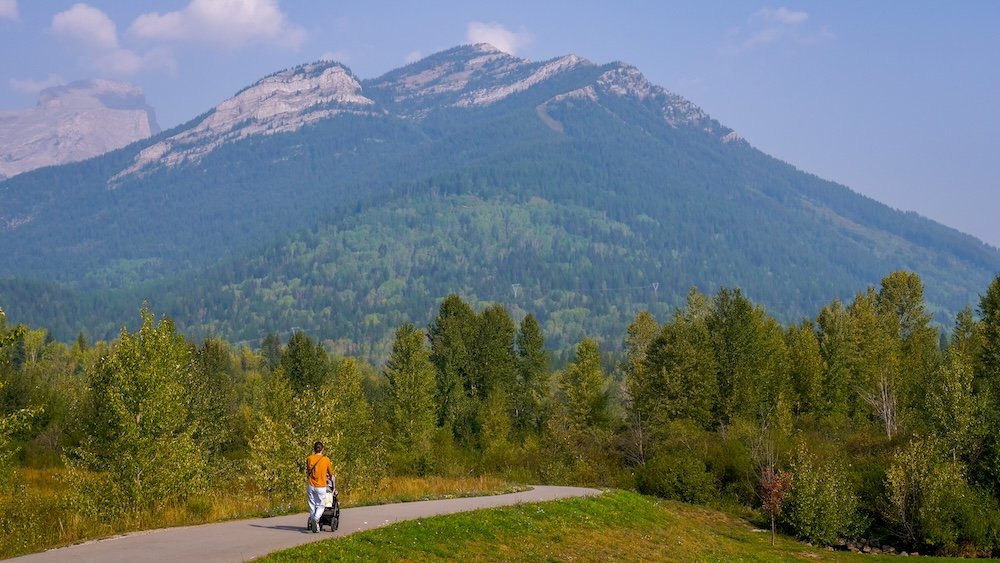 Stroller walk around Maiden Lake in Fernie Maiden Lake in Fernie, British Columbia with sweeping mountain views as Audrey Bergner of That Backpacker pushes baby Aurelia in a stroller along a paved lakeside path, showing an easy, scenic, stroller-friendly walk perfect for family travel.