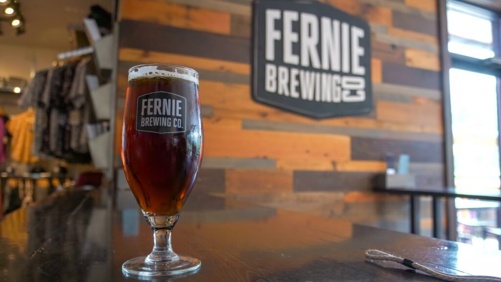 Fernie, British Columbia post-hike beer moment featuring a glass of Ridgewalk Red Ale at Fernie Brewing Company, enjoyed after completing the Fairy Creek Falls trail, capturing the classic trail-to-brewery reward culture that defines hiking days in Fernie.
