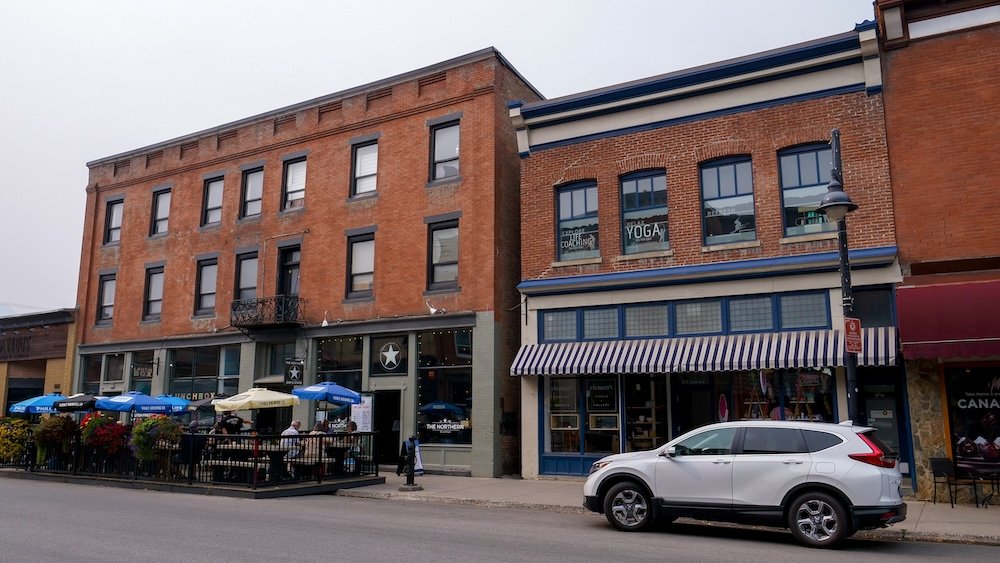 Fernie, British Columbia downtown streetscape showing historic red-brick buildings, local shops, and outdoor patios that reflect Fernie’s relaxed, lived-in mountain town atmosphere and its balance between everyday community life and tourism.
