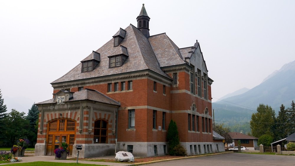 Fernie, British Columbia historic courthouse building with red brick architecture, arched windows, and a mountain backdrop, a prominent downtown landmark and an easy cultural stop to visit while exploring Fernie on a relaxed and rewarding day trip.