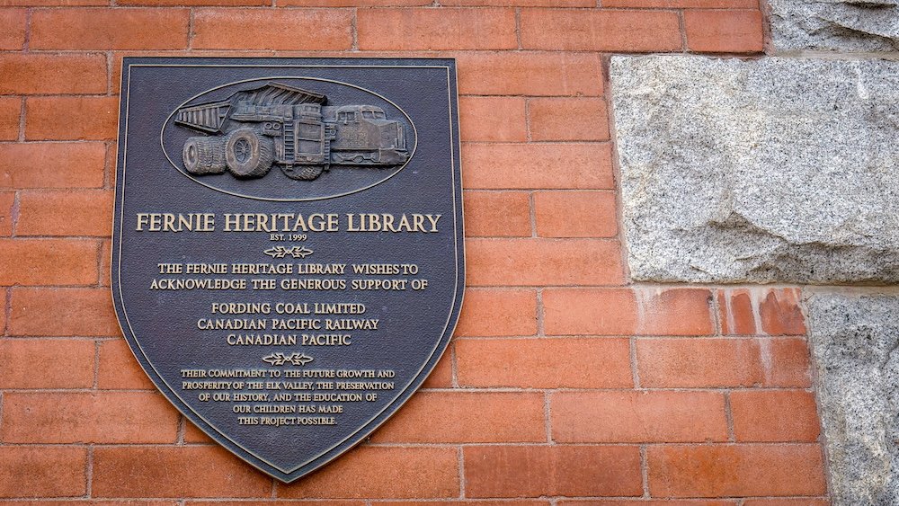 Fernie Heritage Library historical plaque Fernie Heritage Library plaque mounted on a brick wall in downtown Fernie, British Columbia, acknowledging coal and railway companies that supported historical preservation and education following the town’s mining-era growth and rebuilding.