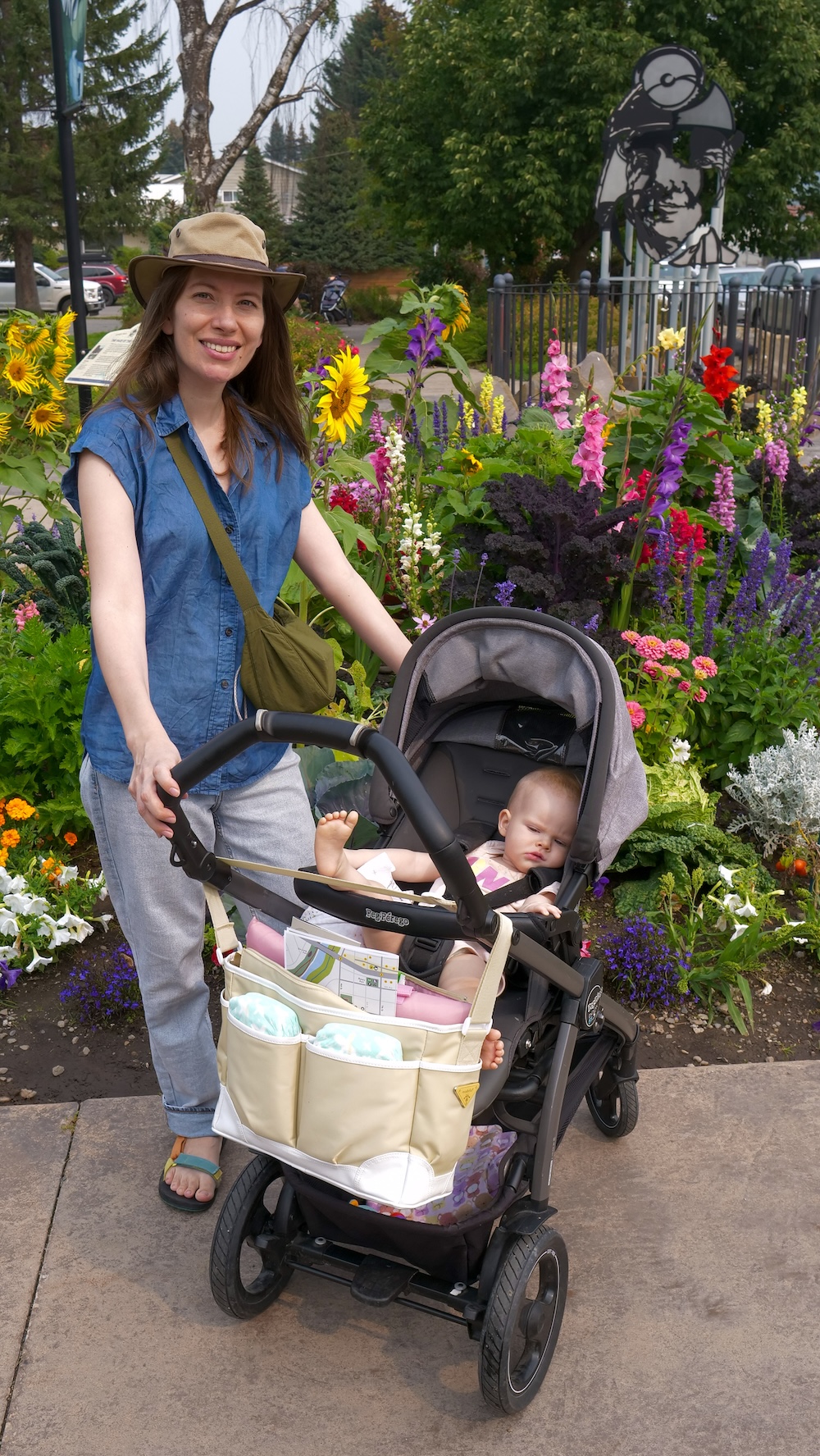 Fernie Heritage Walk flowers near the Miner’s Path Audrey Bergner of That Backpacker pauses with baby Aurelia in a stroller beside colorful flower beds along Fernie’s Heritage Walk near the Miner’s Path, capturing a relaxed, family-friendly moment surrounded by historic downtown scenery and summer blooms.