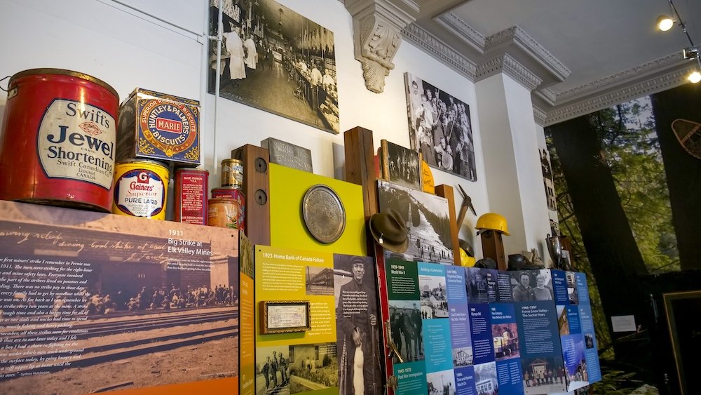 Fernie Museum mining history exhibit Inside the Fernie Museum in Fernie, BC, a detailed exhibit wall displays mining artifacts, historic photos, timelines, and everyday objects that tell the story of coal mining, fires, and community life in this Rocky Mountain town.