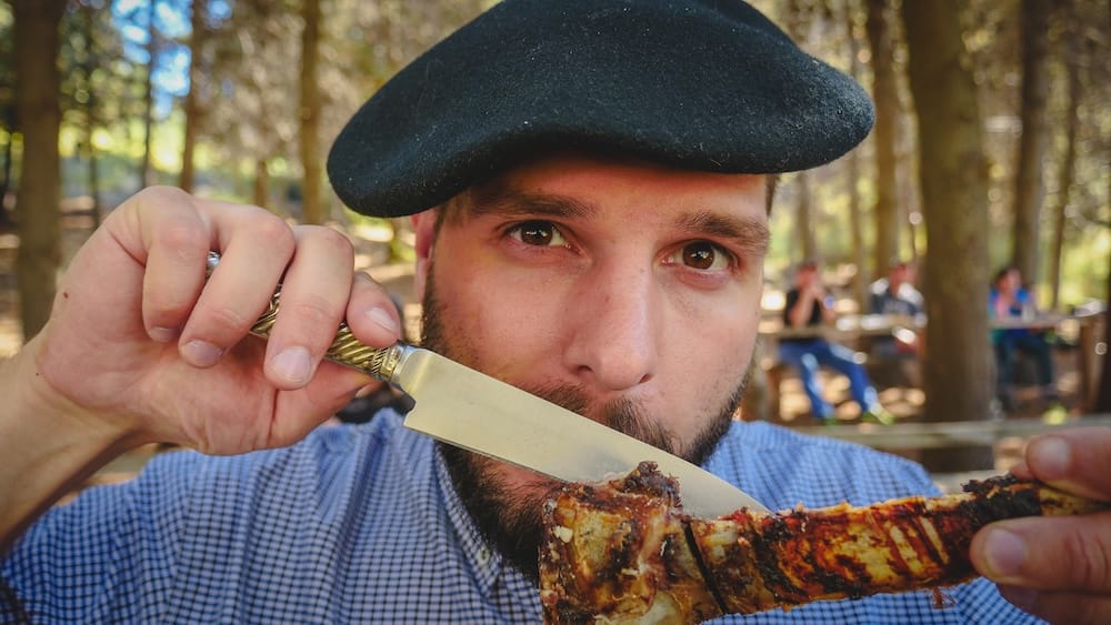 Eating asado with facon knife Cholila gaucho style Patagonia Fiesta Nacional del Asado Cholila Patagonia man eating grilled meat using a facón knife while wearing a beret, showing hands-on gaucho eating style where utensils are secondary to tradition and practicality at rural Argentine gatherings.