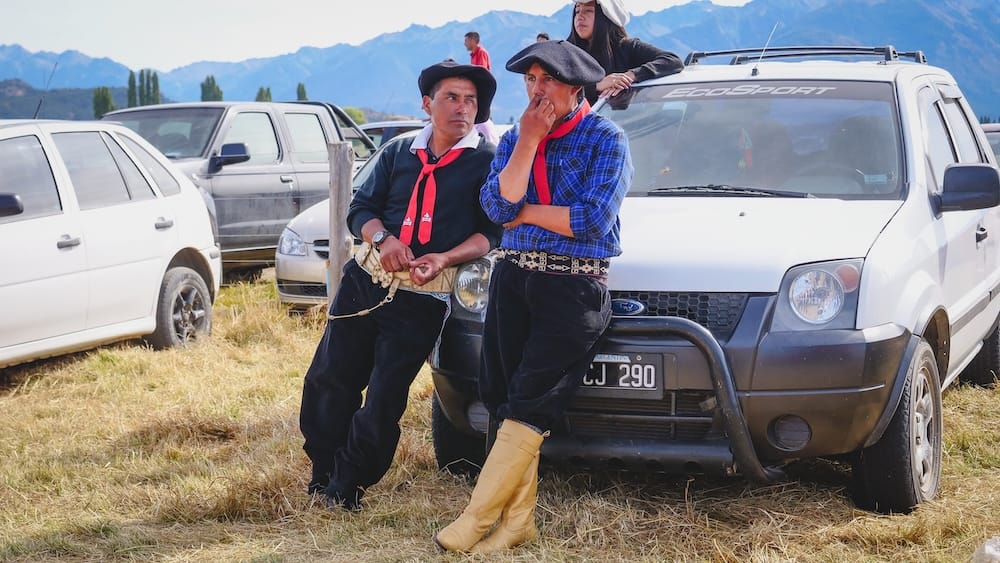 Gauchos at Cholila festival modern rural life Patagonia Fiesta Nacional del Asado Cholila Patagonia gauchos leaning against a vehicle in bombachas and boots, showing modern gaucho life where traditional dress and rural culture intersect with everyday transport at community gatherings.