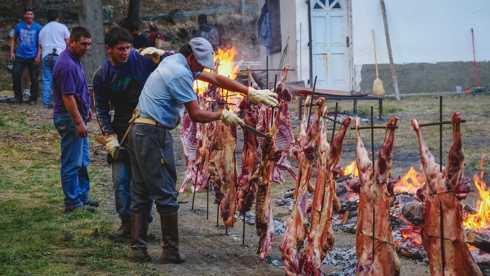 Fiesta Nacional del Asado Cholila Patagonia traditional lamb barbecue over open fire gaucho cooking Cholila, Chubut Patagonia — locals preparing whole lambs over open flames at the Fiesta Nacional del Asado, showcasing traditional Patagonian barbecue techniques, gaucho culture, and the communal spirit of one of Argentina’s most authentic rural festivals.