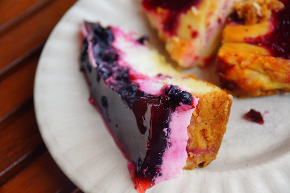 A slice of Finnish berry dessert with dark blueberries, creamy filling and a golden crust served alongside other fruit pastries at Farmors Cafe on Högsåra Island in Finland.
