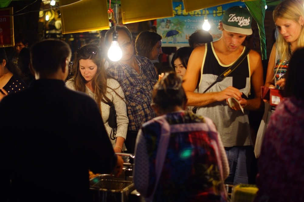 Foreigners eating street food at night in Chiang Mai, Thailand 