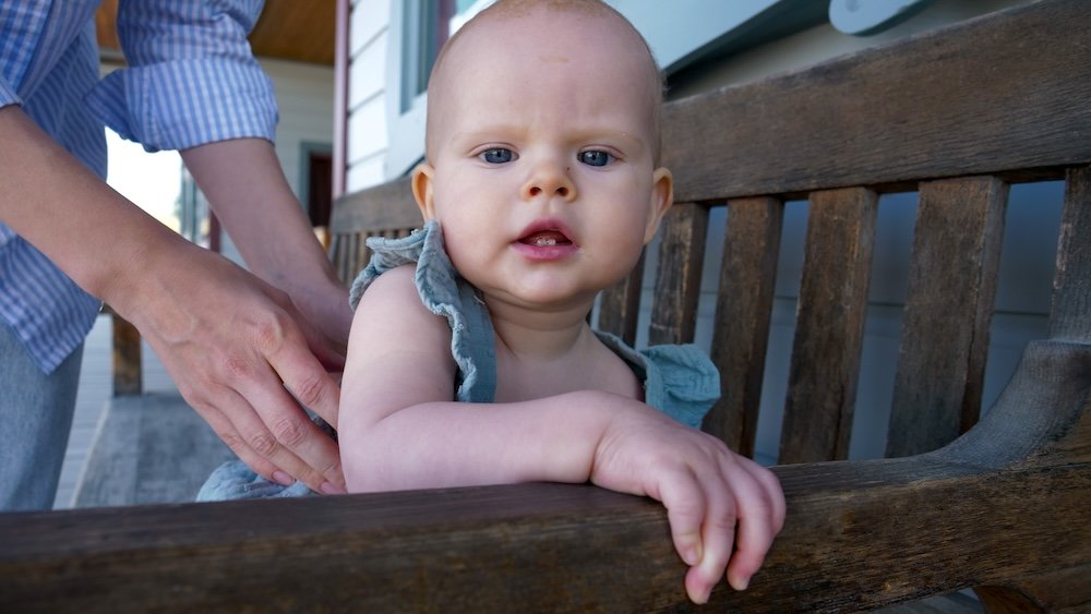 Fort Steele Heritage Town near Cranbrook, BC, showing baby Aurelia enjoying a relaxed moment on a wooden bench during a family day trip, capturing how easy and calm this historic open-air site can be when visiting with kids.