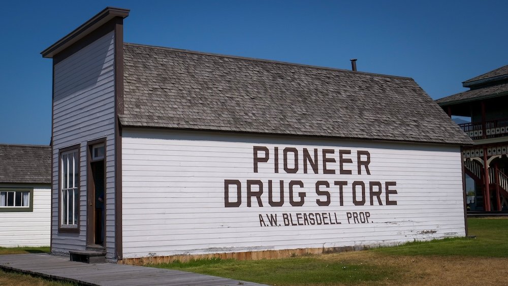 Pioneer Drug Store at Fort Steele Heritage Town near Cranbrook, BC, with its simple wooden exterior and painted signage, illustrating how frontier-era pharmacies supplied medicine, remedies, and everyday essentials in a working boomtown community.
