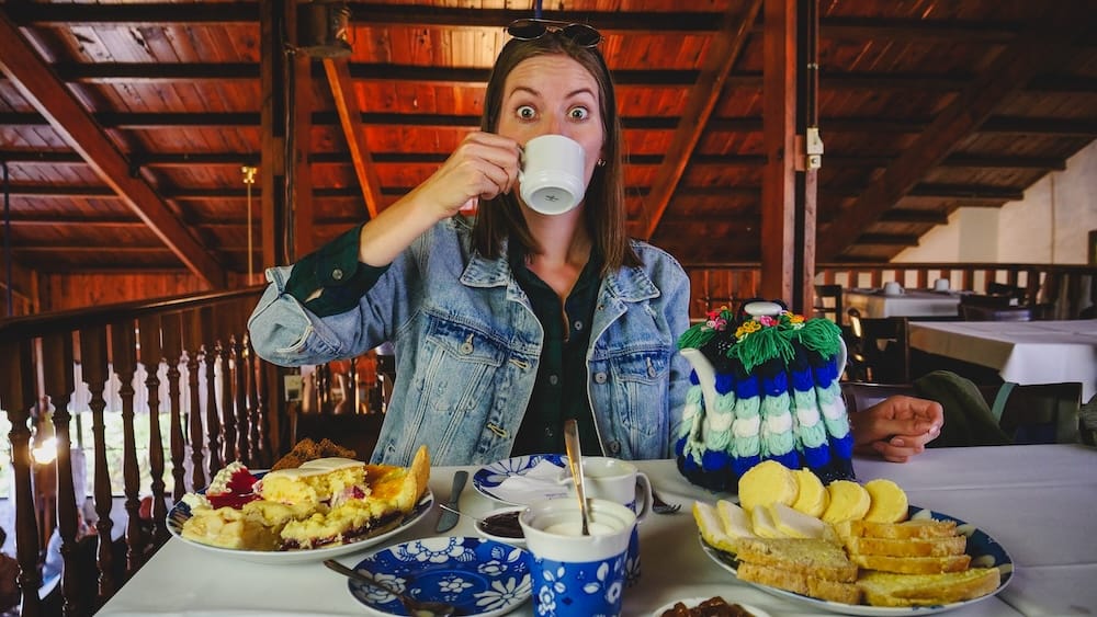 Audrey Bergner drinking tea during a traditional Welsh tea merienda in Gaiman, Argentina surrounded by scones, sandwiches, and cakes including Torta Negra Galesa, capturing Patagonia’s ceremonial afternoon tea experience.
