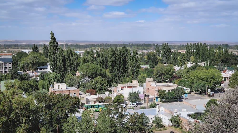 Panoramic view of Gaiman in Patagonia showing lush green trees along the Chubut River surrounded by dry desert steppe, highlighting the contrast that defines this historic Welsh settlement in southern Argentina