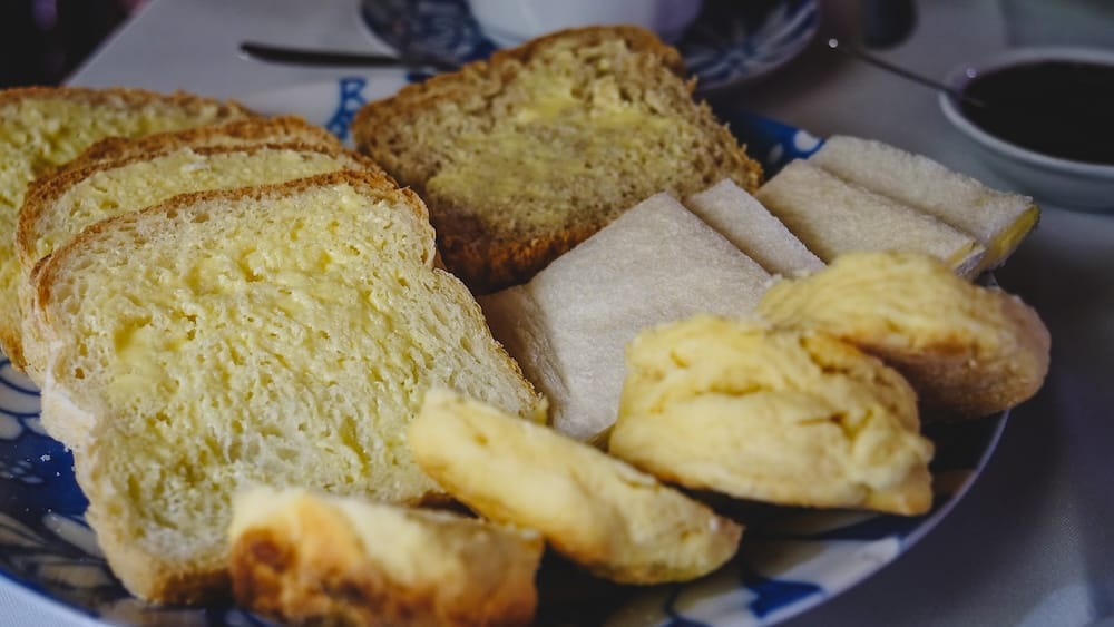 Buttered bread and scones in Gaiman Patagonia forming the savory base of traditional Welsh tea service Buttered bread, traditional scones, and simple tea sandwiches served during Welsh tea in Gaiman, Patagonia, highlighting the foundational savory layer that balances rich desserts in the classic té galés experience in Argentina.