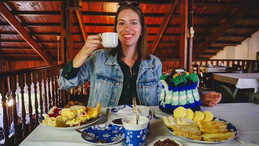 Audrey Bergner enjoying traditional Welsh tea in Gaiman at Ty Gwyn, Patagonia, with homemade cakes, bread, and a decorated teapot, highlighting how Welsh culinary traditions continue to thrive in southern Argentina generations after settlement.