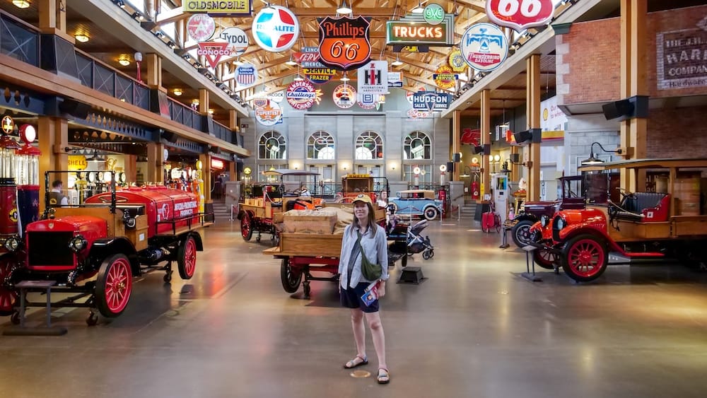 Audrey Bergner dentro de Gasoline Alley Museum con autos antiguos y carteles, Calgary, Alberta, Canadá Audrey Bergner está dentro de Gasoline Alley Museum, en Calgary, Alberta, Canadá, rodeada de autos antiguos, surtidores históricos de nafta y coloridos carteles automotrices colgados sobre la gran sala de exhibición.