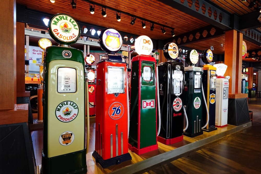 Surtidores antiguos de nafta y carteles luminosos dentro de Gasoline Alley Museum, Calgary, Alberta, Canadá Una fila de coloridos surtidores antiguos de nafta y carteles luminosos de marcas de combustible dentro de Gasoline Alley Museum, en Calgary, Alberta, Canadá, exhibidos bajo un techo de madera.