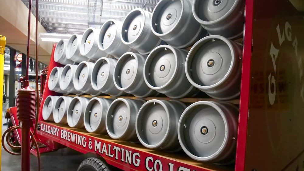 Rows of metal kegs stacked on a vintage Calgary Brewing & Malting Co. delivery display inside Gasoline Alley Museum at Heritage Park in Calgary, Alberta, Canada.