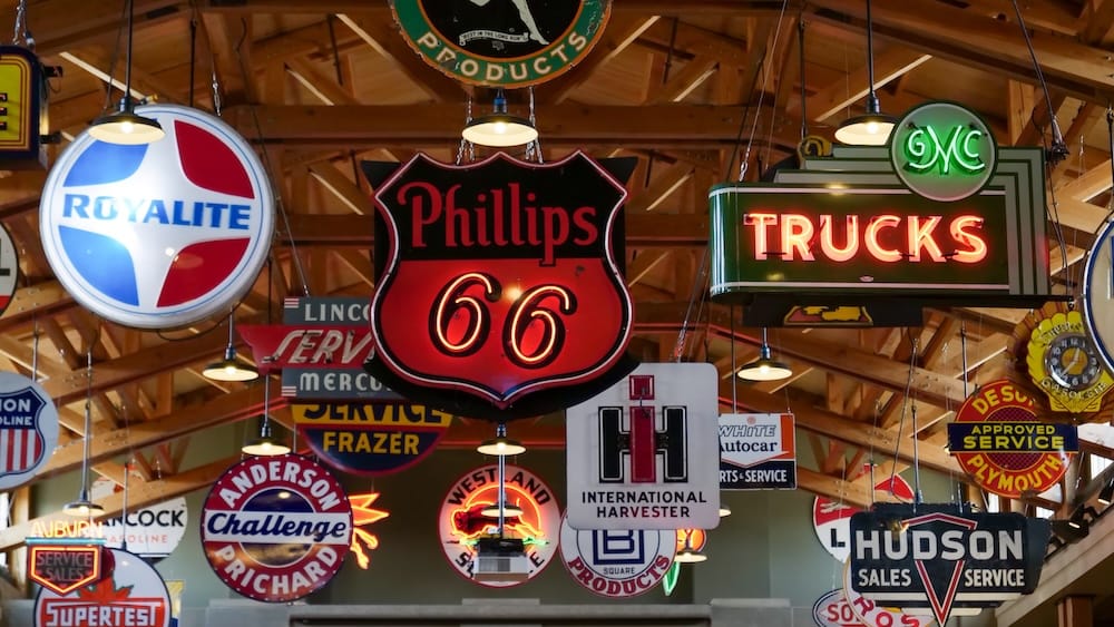 Vintage automotive and petroleum signs hanging from the rafters inside Gasoline Alley Museum at Heritage Park in Calgary, Alberta, Canada, including Phillips 66, Royalite, GMC Trucks and Hudson branding.