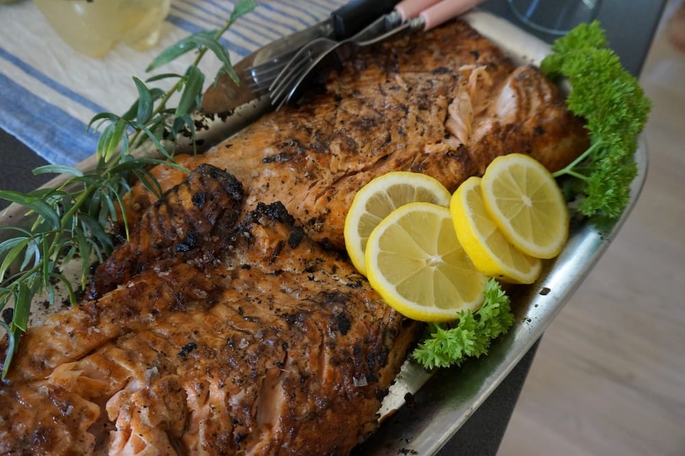 Grilled fish served with lemon slices and fresh herbs on Lonna Island near Helsinki, capturing a simple Finnish summer meal in the archipelago built around fresh seafood and seasonal ingredients.
