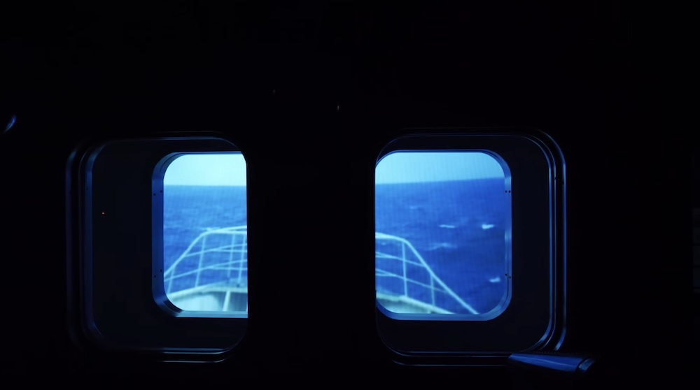 Projected sea view inside the fishing-boat simulator, Hakodate City Hokuyo Museum, Hokkaido, Japan Two porthole-style windows in the darkened simulator booth at the Hakodate City Hokuyo Museum in Goryokaku, Hakodate, Hokkaido, Japan, showing a projected choppy blue sea and the railed bow of a fishing boat.