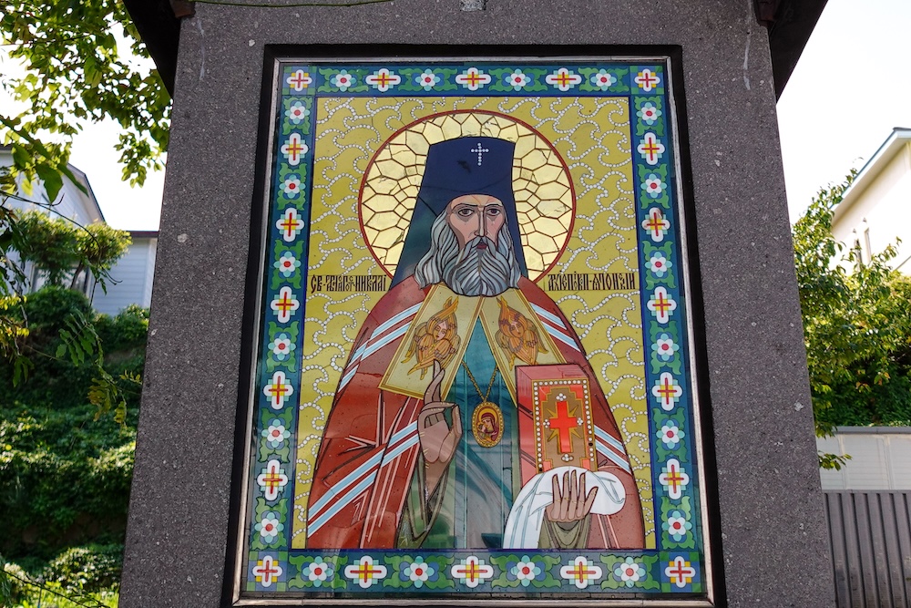 Colourful Orthodox icon depicting Saint Nicholas of Japan at Hakodate Orthodox Church in Motomachi, Hakodate, Hokkaido, Japan, showing the bearded saint holding a decorated religious book against a golden background.